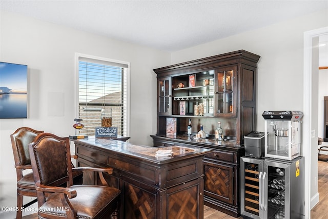 bar with dark brown cabinetry, light hardwood / wood-style flooring, and wine cooler