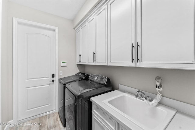 laundry area with sink, cabinets, light hardwood / wood-style flooring, and washing machine and dryer