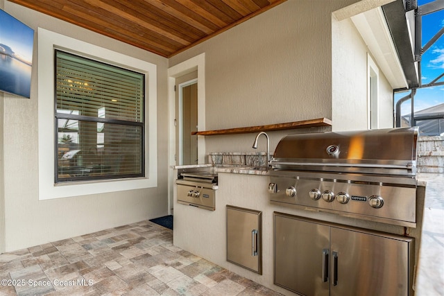 view of patio with glass enclosure, an outdoor kitchen, and grilling area