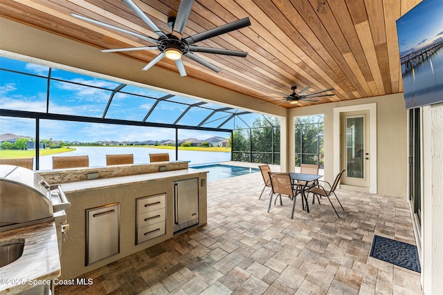 view of patio / terrace featuring exterior kitchen, area for grilling, ceiling fan, and a water view