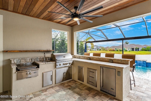 view of patio featuring pool water feature, exterior kitchen, grilling area, and a lanai