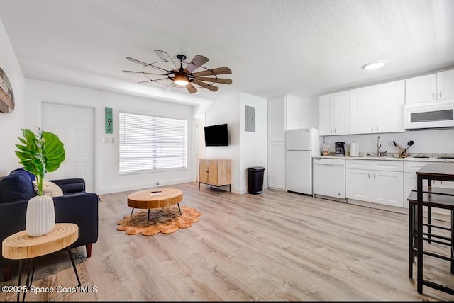 interior space with light wood-type flooring, ceiling fan, a textured ceiling, electric panel, and sink