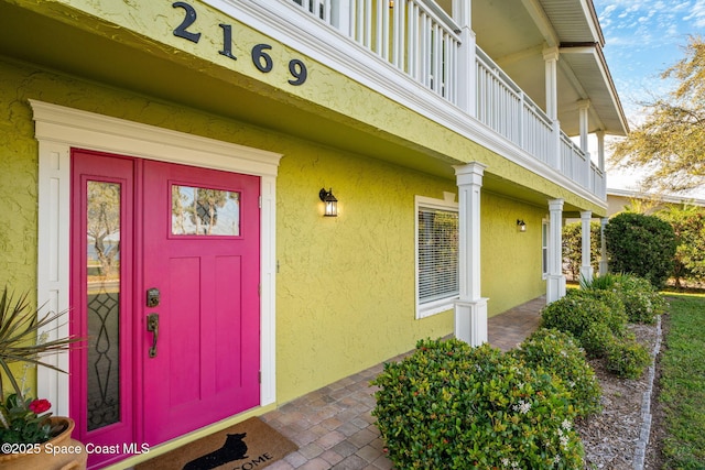 entrance to property with a balcony and stucco siding