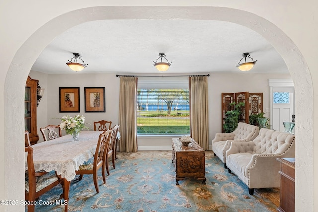 dining area featuring baseboards, arched walkways, and a textured ceiling