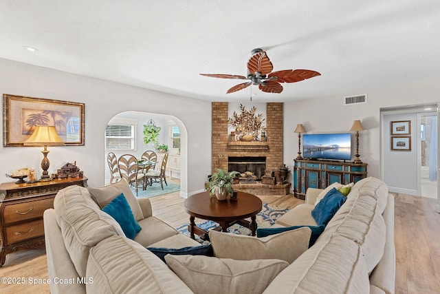 living area with light wood-style floors, baseboards, a fireplace, and visible vents