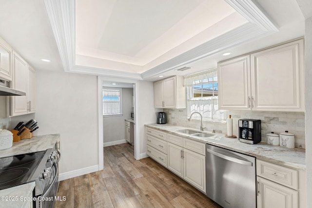 kitchen featuring stainless steel appliances, a sink, visible vents, backsplash, and a tray ceiling