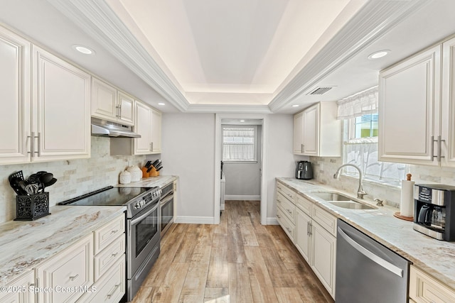 kitchen with a tray ceiling, visible vents, appliances with stainless steel finishes, a sink, and under cabinet range hood