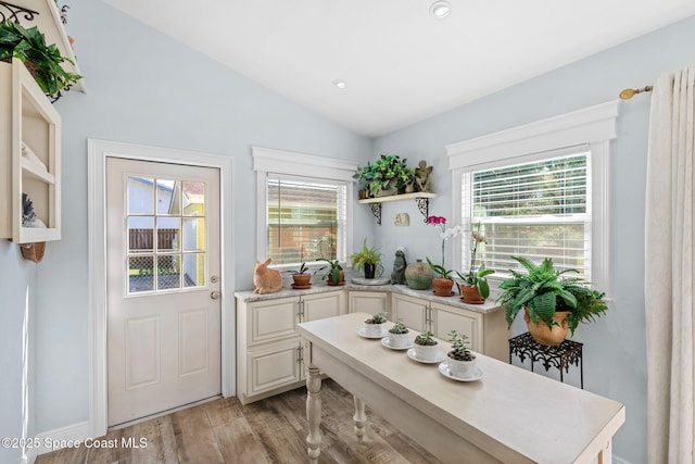 doorway to outside featuring light wood-style flooring and vaulted ceiling