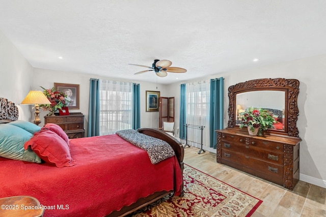 bedroom with ceiling fan, multiple windows, baseboards, and wood finished floors