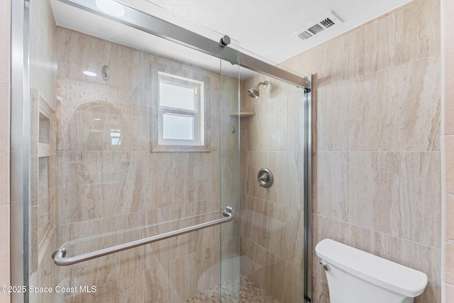 full bath featuring toilet, a stall shower, and visible vents