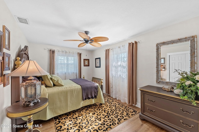 bedroom featuring light wood-type flooring, ceiling fan, and visible vents