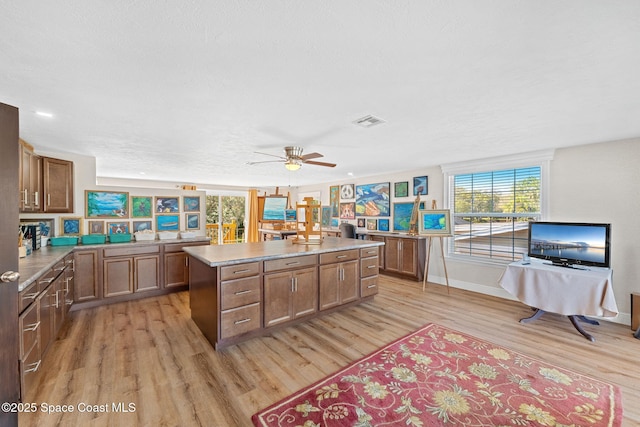 kitchen featuring light countertops, visible vents, light wood-style floors, a ceiling fan, and a kitchen island