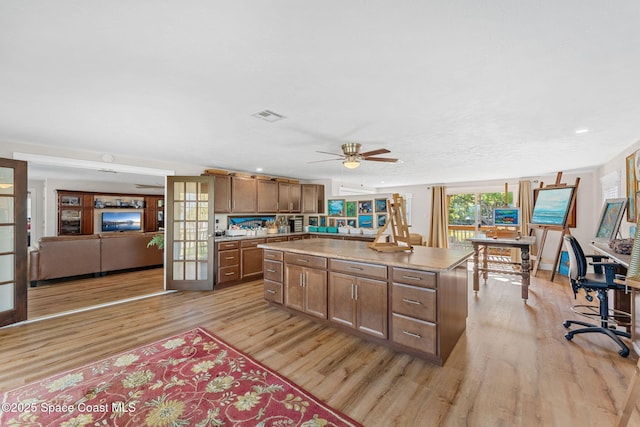 kitchen with a center island, visible vents, light wood-style floors, brown cabinetry, and a ceiling fan