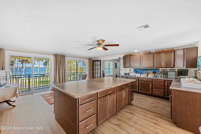 kitchen with light wood-type flooring, a center island, visible vents, and a ceiling fan