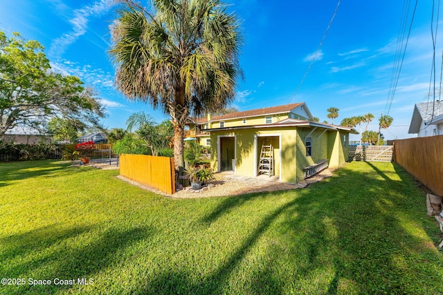 back of property with a yard, a fenced backyard, and stucco siding