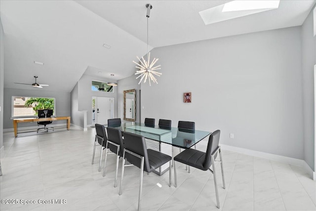 dining room featuring vaulted ceiling with skylight and ceiling fan with notable chandelier