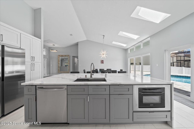 kitchen with appliances with stainless steel finishes, sink, gray cabinetry, and lofted ceiling with skylight