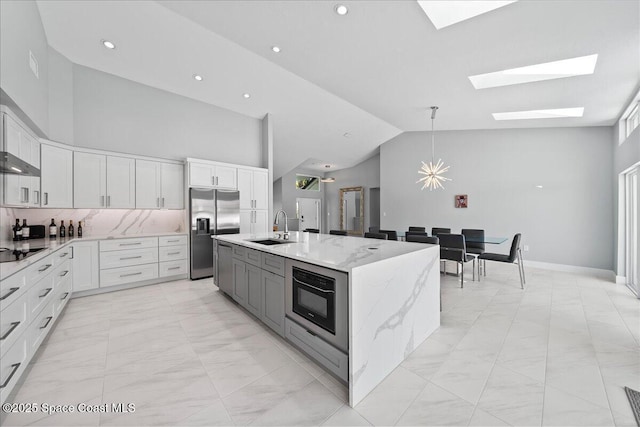 kitchen with black appliances, sink, white cabinetry, and a center island with sink