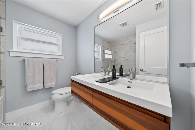 bathroom with toilet, tiled shower, and vanity