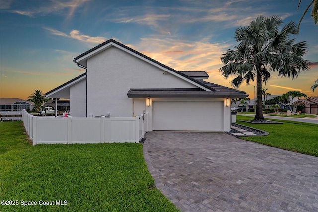 property exterior at dusk featuring a garage and a yard