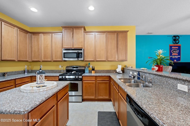 kitchen with appliances with stainless steel finishes, light stone counters, sink, and light tile patterned floors