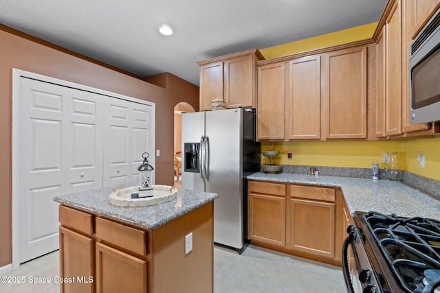 kitchen featuring light stone countertops, appliances with stainless steel finishes, and a center island