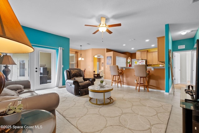 living room featuring a textured ceiling, ceiling fan, and light tile patterned floors