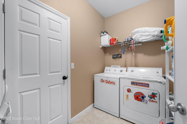 laundry area with washer and clothes dryer, a textured ceiling, and light tile patterned floors