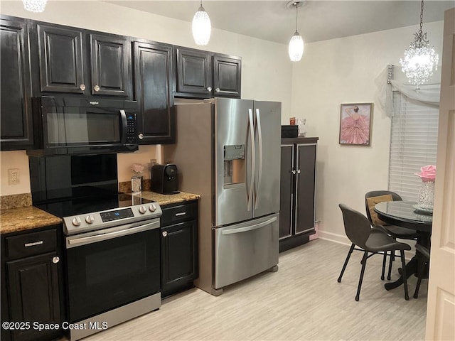 kitchen with appliances with stainless steel finishes, pendant lighting, a notable chandelier, and light stone counters