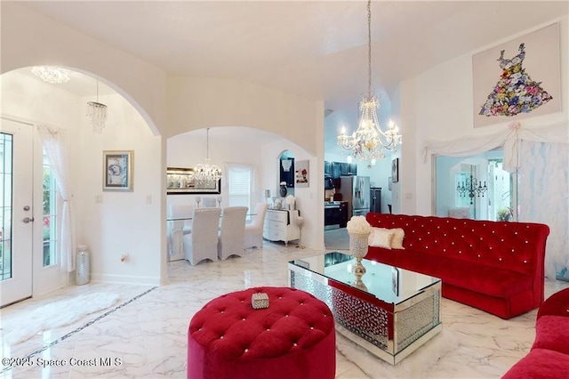 living area with marble finish floor, plenty of natural light, arched walkways, and a notable chandelier