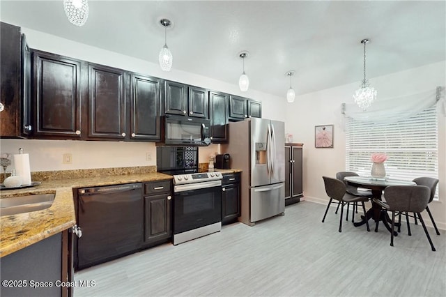 kitchen with light wood-style flooring, light stone counters, pendant lighting, dark brown cabinetry, and black appliances