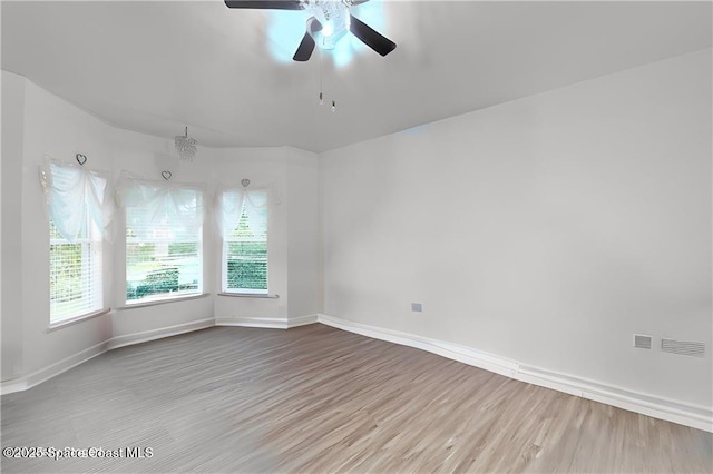 empty room featuring a ceiling fan, baseboards, and wood finished floors