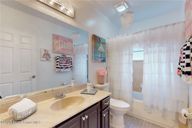 bathroom with toilet, an inviting chandelier, shower / tub combo with curtain, and vanity