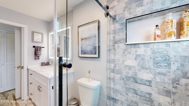 bathroom featuring toilet, vanity, and a tile shower