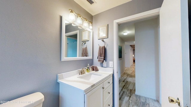 bathroom with toilet, hardwood / wood-style floors, and vanity