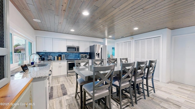 dining space featuring wood ceiling, light hardwood / wood-style flooring, and sink