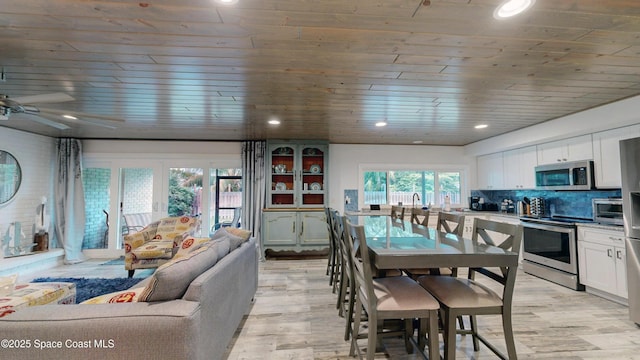 dining space with ceiling fan, light hardwood / wood-style floors, and wooden ceiling