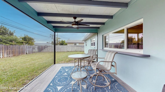 sunroom with ceiling fan and beamed ceiling