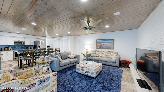 living room featuring ceiling fan, brick wall, light hardwood / wood-style flooring, and wood ceiling