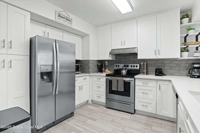 kitchen with stainless steel appliances, white cabinetry, light wood-type flooring, and decorative backsplash