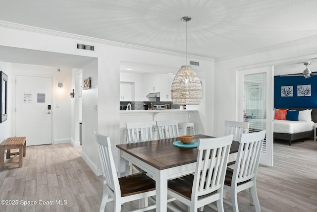 dining area with light hardwood / wood-style floors and crown molding