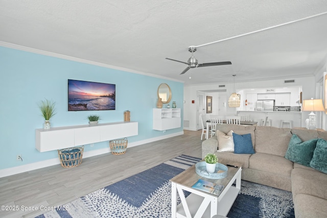 living room with a textured ceiling, hardwood / wood-style floors, ceiling fan, and crown molding