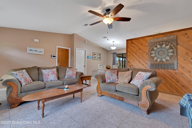 living room with ceiling fan, light tile patterned flooring, wooden walls, and lofted ceiling