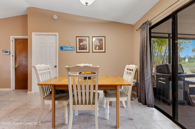 dining space featuring lofted ceiling and light tile patterned floors