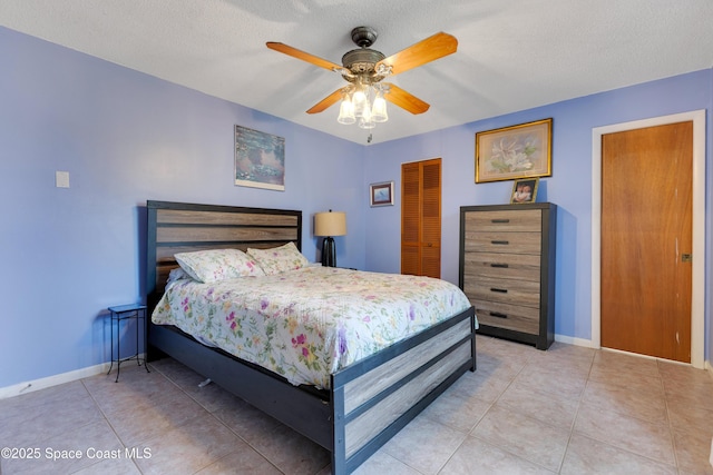 tiled bedroom with a textured ceiling, ceiling fan, and a closet