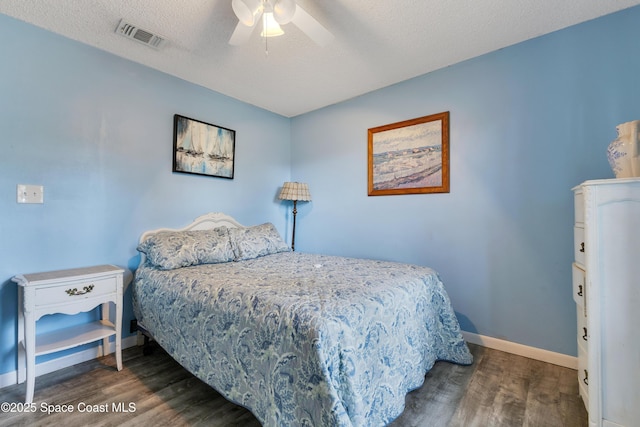 bedroom with ceiling fan, dark hardwood / wood-style floors, and a textured ceiling