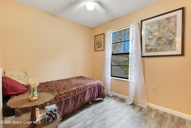 bedroom with ceiling fan, light hardwood / wood-style floors, and a textured ceiling