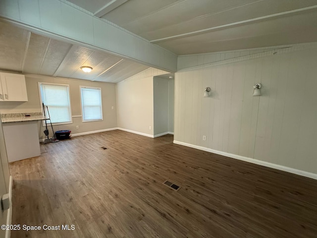 unfurnished living room with dark hardwood / wood-style flooring and vaulted ceiling with beams