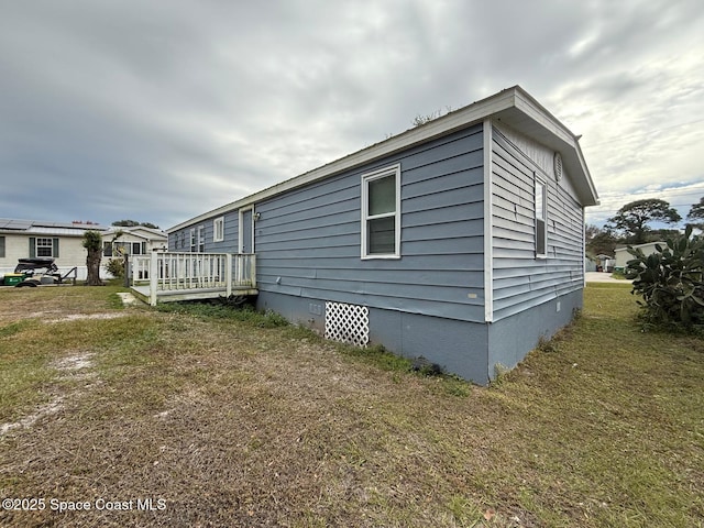 view of side of home featuring a lawn and a deck