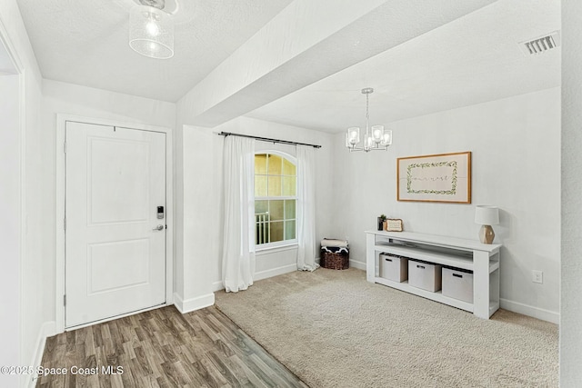 foyer with wood-type flooring, a chandelier, and a textured ceiling